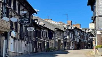 Une rue étroite bordée de bâtiments traditionnels, dont un hôtel appelé « Creperie Du Mont Hotel ».