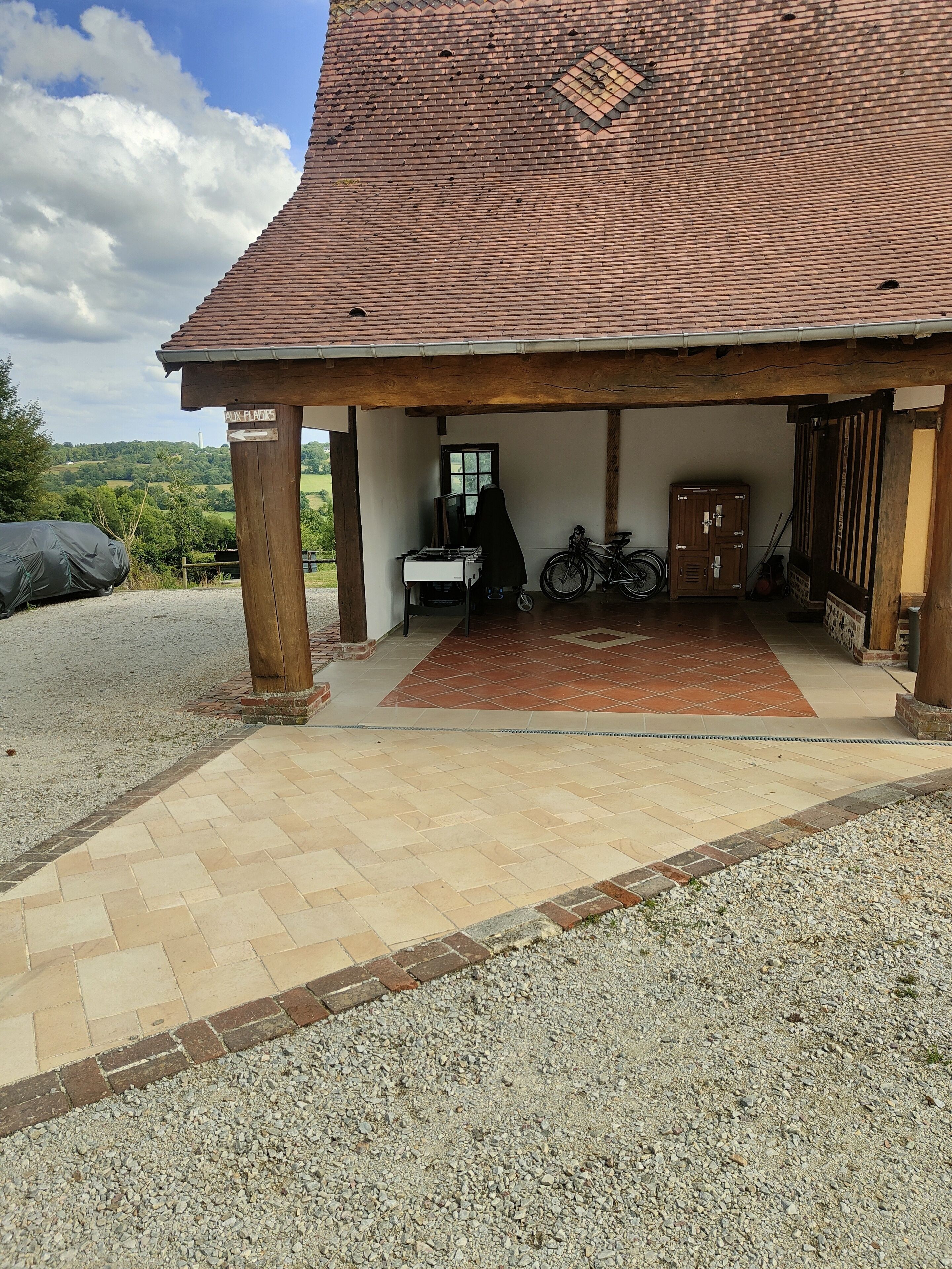 A covered outdoor area with a tiled floor, a wooden bench, and a bicycle.