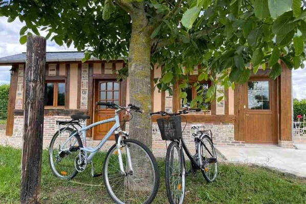 Un edificio con fachada de ladrillo, ventanas grandes y puerta de madera. Dos bicicletas estacionadas adelante.