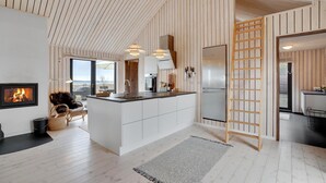 A modern kitchen with a central island, wooden panel walls, and a view to the outside.