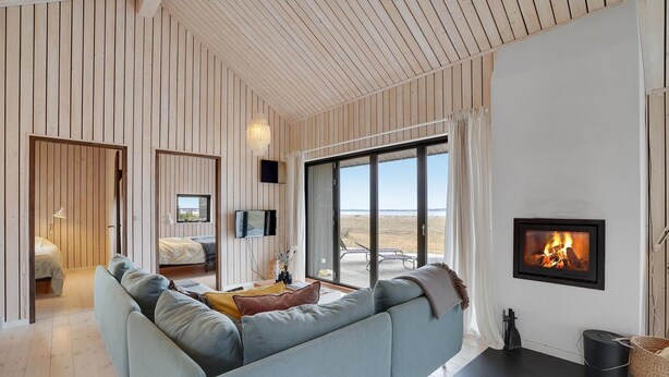 A modern living room with a large sofa, a fireplace, and a view of the outdoors.