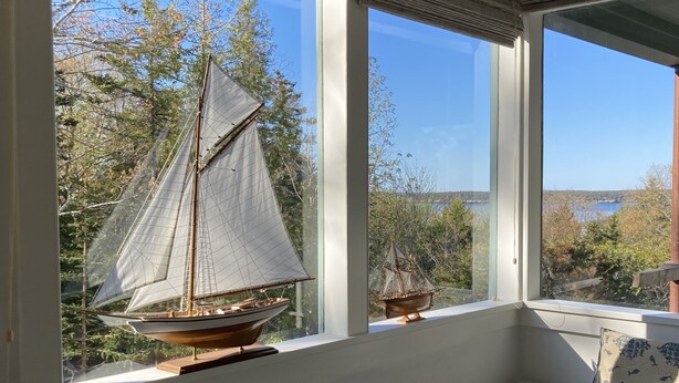 Ein Zimmer mit großem Fenster, einer eingebauten Sitzbank und einem kleinen Modell eines Segelboots.