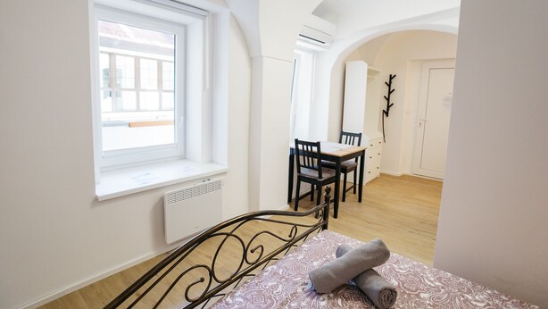 Ein Schlafzimmer mit Bett, Fenster, Heizkörper, Schreibtisch und Stuhl.