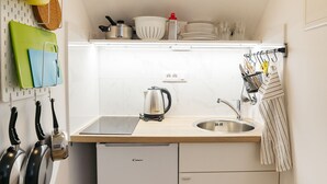 Eine kleine Küche mit Spüle, Wasserkocher und verschiedenen Kochutensilien.