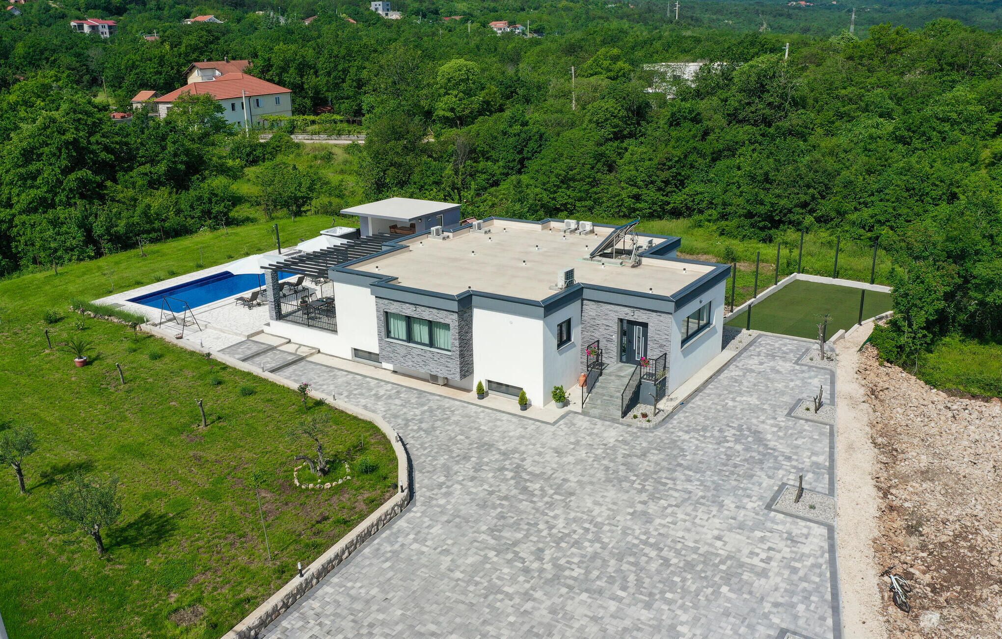 A modern house with a flat roof, a swimming pool, and a well-maintained garden.