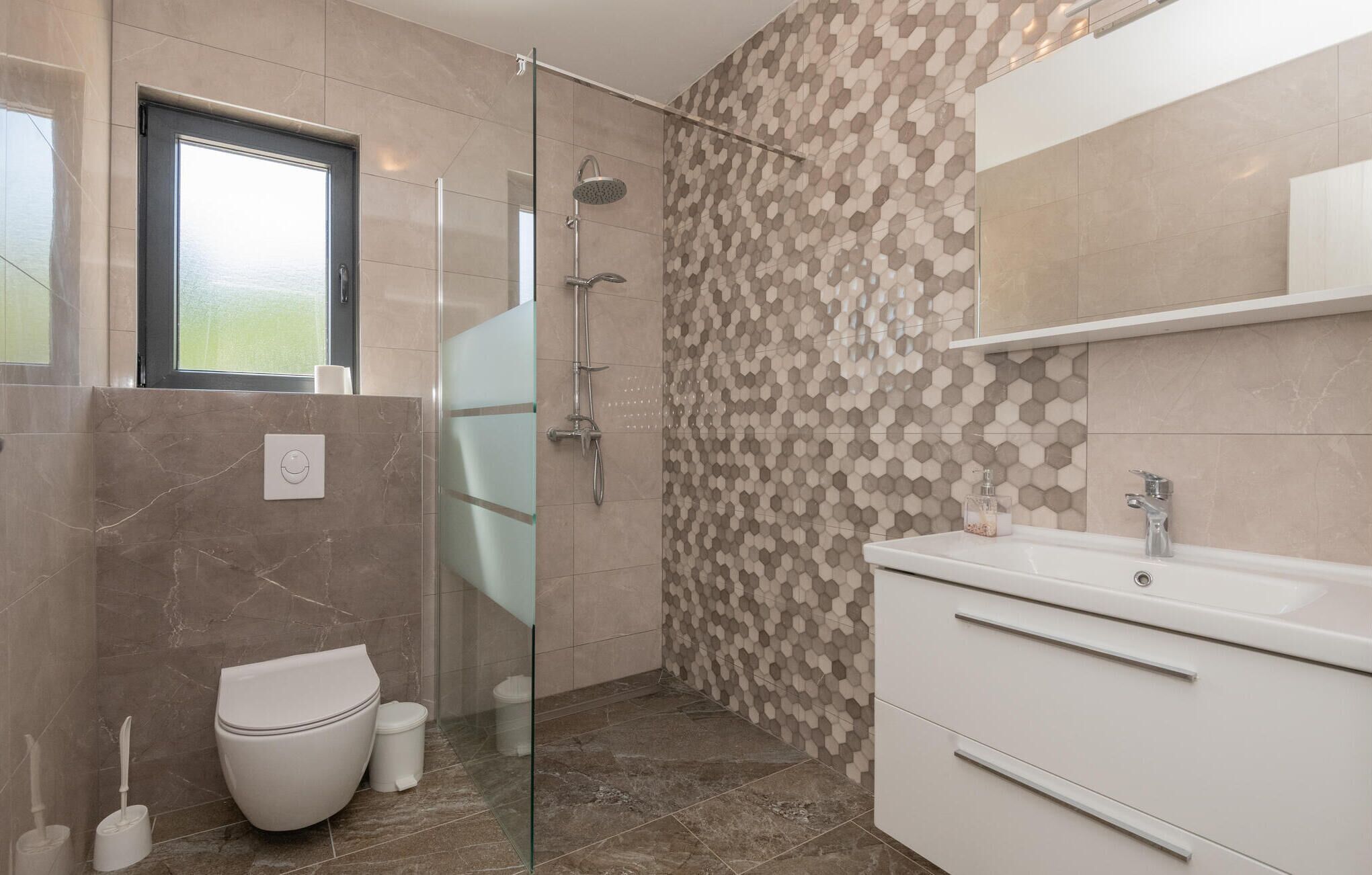 A modern bathroom with a glass shower enclosure, a toilet, and a vanity with a mirror.