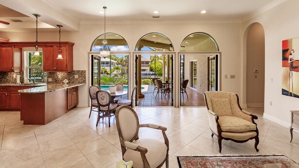 A spacious kitchen with a large island, wooden cabinets, and a dining area with chairs and a table. - LUXURY HOUSE BY THE CANAL ☀️ (Siesta Key)