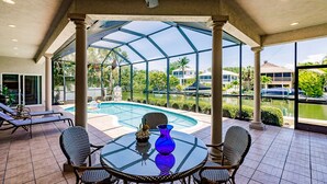 A covered outdoor area with a glass enclosure, a pool, and lounge chairs. - LUXURY HOUSE BY THE CANAL ☀️ (Siesta Key)