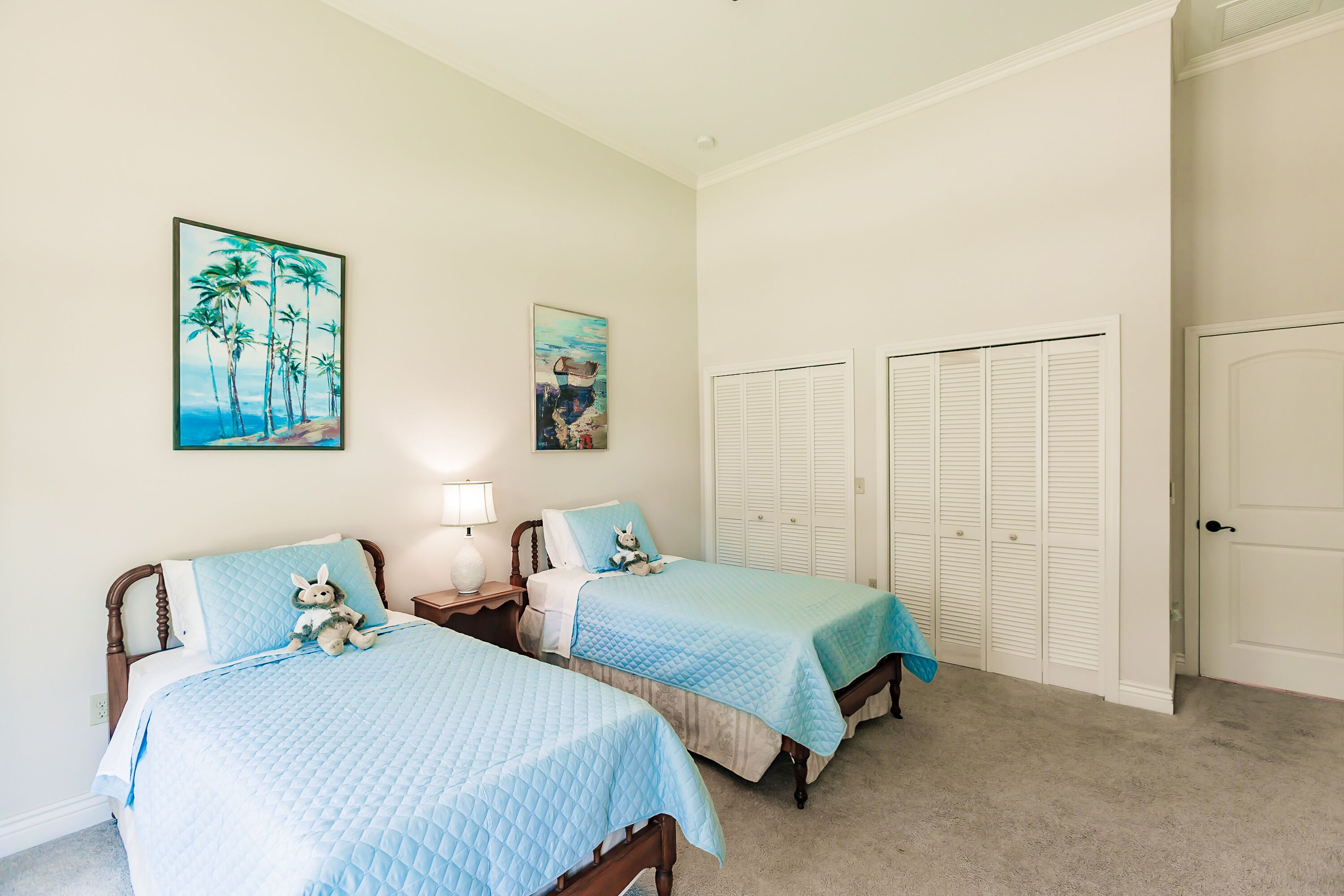 A bedroom with two beds, a nightstand, a lamp, and a door to a closet.