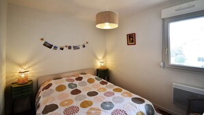 Ein Schlafzimmer mit einem Bett, zwei Nachttischlampen, einer Wandleuchte, einem Fenster und einer Wanddekoration.