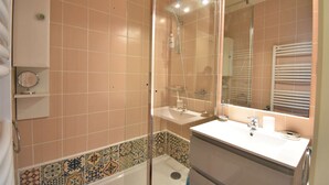 Ein Badezimmer mit Dusche, Waschbecken und Spiegel.