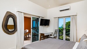 Una habitación de hotel con cama, escritorio, televisor y balcón con vistas.