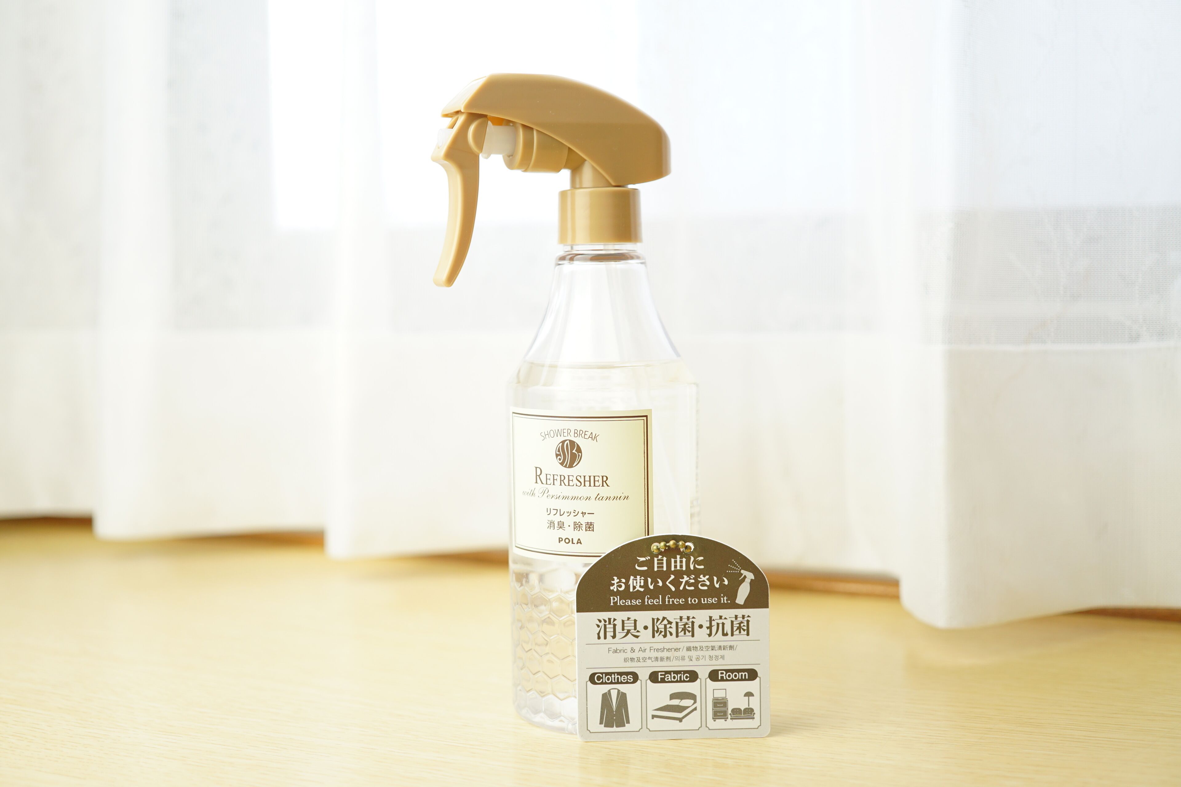A spray bottle with a label and a tag on a wooden surface.