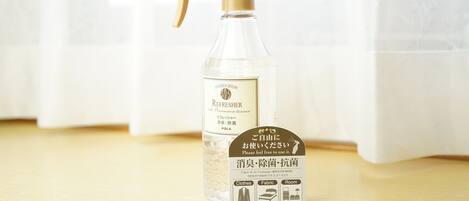 A spray bottle with a label and a tag on a wooden surface.