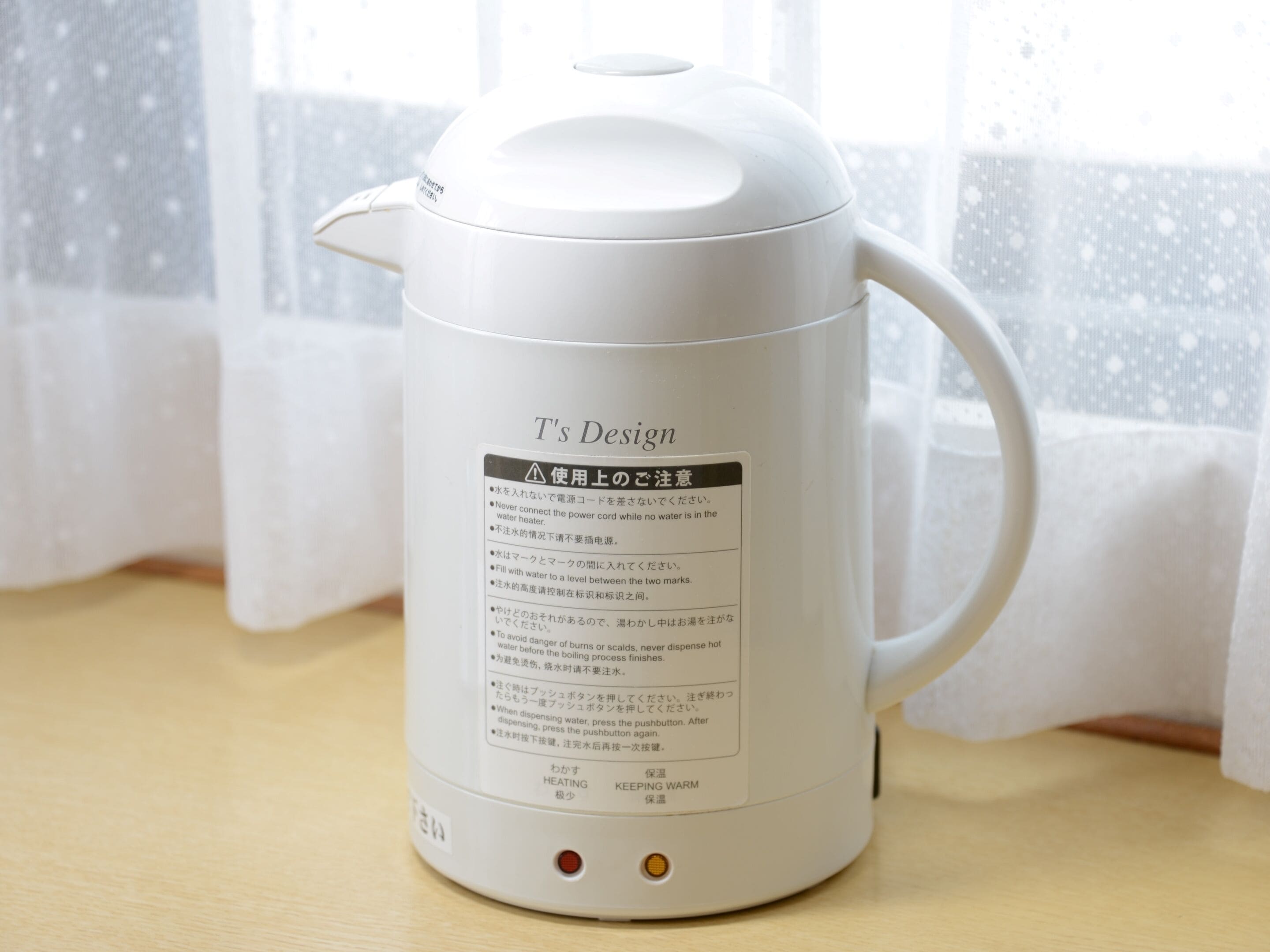 A white electric kettle with a label that includes safety instructions and temperature settings.