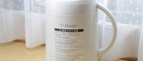 A white electric kettle with a label that includes safety instructions and temperature settings.