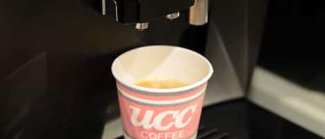 A coffee machine dispensing coffee into a branded paper cup.