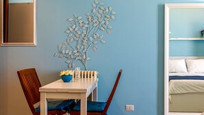 A room with a dining table, chairs, a decorative wall piece, and a bed with a white frame. - Pippo House Beach Front (Giardini Naxos)