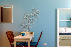 Relax in a serene space with a comfortable bed, a stylish radiator, and a charming table with a vase of flowers.