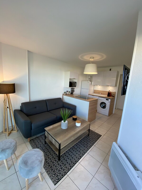 A modern apartment with a living area, a kitchen, and a small dining space.
