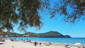 A beach with people sunbathing, umbrellas, and a clear view of the sea and hills in the background. - Lovely apartment for 6 guests with WIFI, A/C, TV and terrace (Saint-cyr-sur-mer)