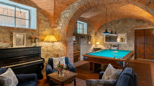 Um quarto acolhedor com mesa de bilhar, piano e assentos confortáveis.