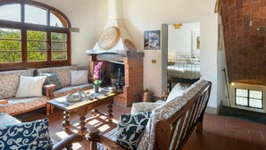 Uma sala de estar acolhedora com lareira, um sofá, uma mesa de centro de madeira e uma janela grande.