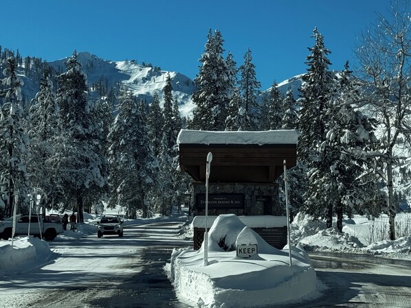 Una carretera nevada con un cartel de madera que indica un complejo turístico y balneario.