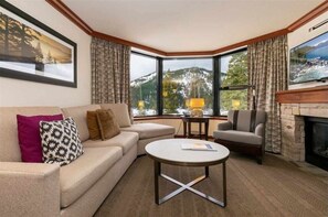 Relax in this stylish living room with a fireplace, comfortable seating, and breathtaking mountain views.