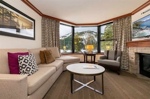 Relax in this stylish living room with a fireplace, comfortable seating, and breathtaking mountain views.
