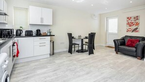 A compact living space with a kitchenette, dining area, and seating area. - Cosy 2BR Maisonette near Hospital & Stations (Bedford)