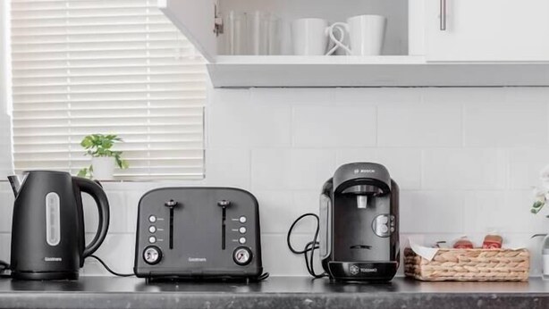 A kitchen with white cabinets, a black coffee maker, a toaster, and a kettle on the counter. - Cosy 2BR Maisonette near Hospital & Stations (Bedford)