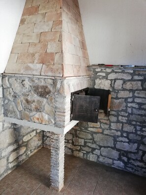 Cozy stone fireplace with a functional metal door and rustic stone walls.