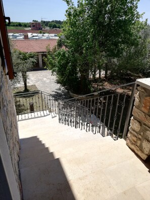 Staircase leads to an outdoor area with a tree and a view of a nearby building.