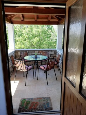 A covered patio with a round table and chairs, stone walls, and a view of greenery. - Villa Valeta 500 meters from the beach (Tar)
