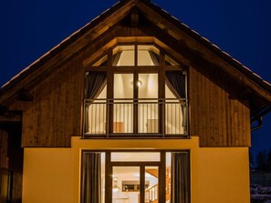 Una casa a due piani in legno, con ampie finestre e un balcone.