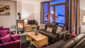 Una sala de estar acogedora con chimenea, un sofá, una mesa de centro y un televisor.