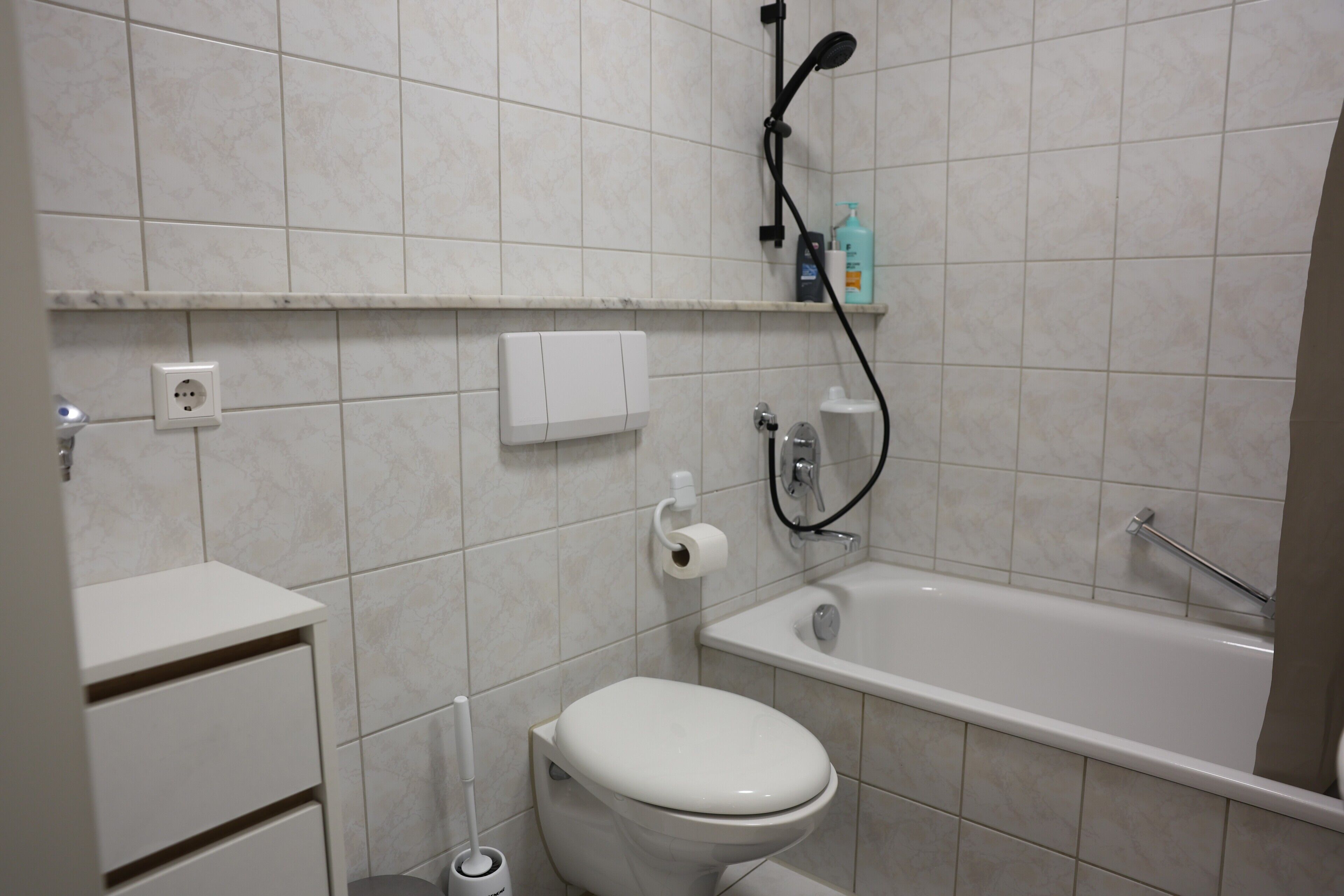 Un bagno con il water, un lavandino, una vasca e una doccetta.