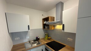 Eine kleine Küche mit Spüle, Herd, Backofen und einer Holz Arbeitsplatte.