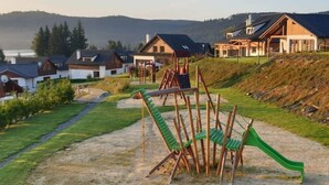 Zona residencial con casas, un parque infantil y un paisaje montañoso.