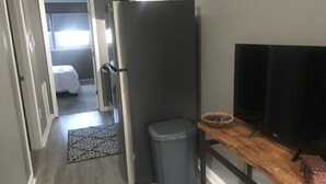Une cuisine compacte comprenant un réfrigérateur, une poubelle, une table en bois et un téléviseur.