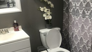 Une salle de bain avec des toilettes, un lavabo et une petite étagère au-dessus des toilettes.