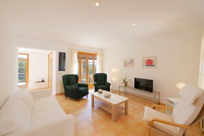 A living room with a sofa, two armchairs, a coffee table, a TV, and artwork on the walls.