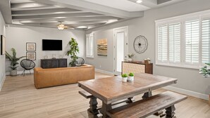 A spacious living area with a wooden dining table, a sofa, and a ceiling fan. - Three Trees Saltwater Pool Place-Heated Pool (El Paso)