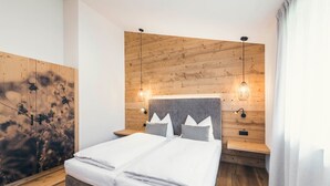 A double bed with white linens, a wooden headboard, two bedside tables with lamps, and a wooden wall panel.