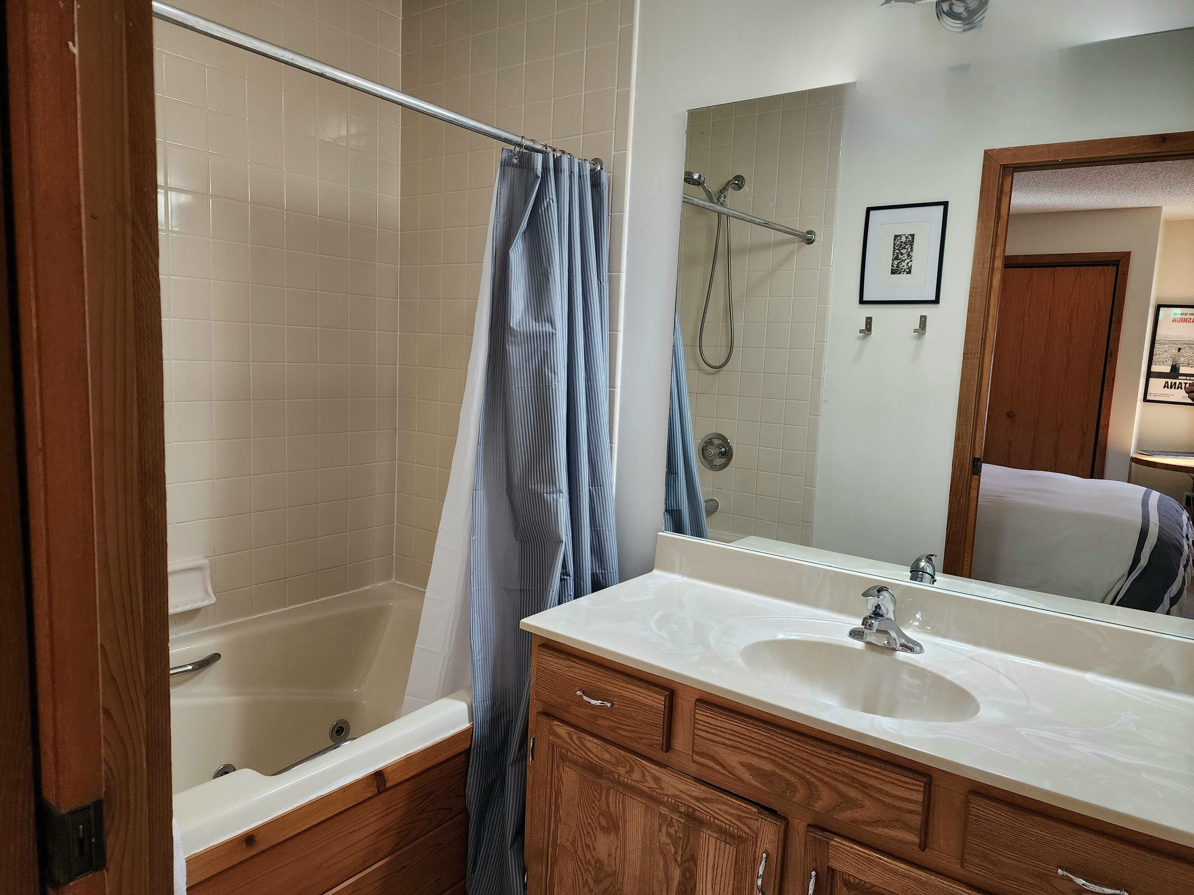 A bathroom with a bathtub, a shower, a sink, and wooden cabinets.