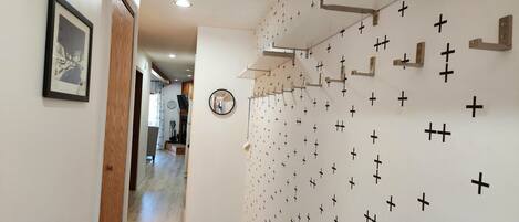 A hallway with a wall decorated with black crosses, a framed picture, and a round mirror.