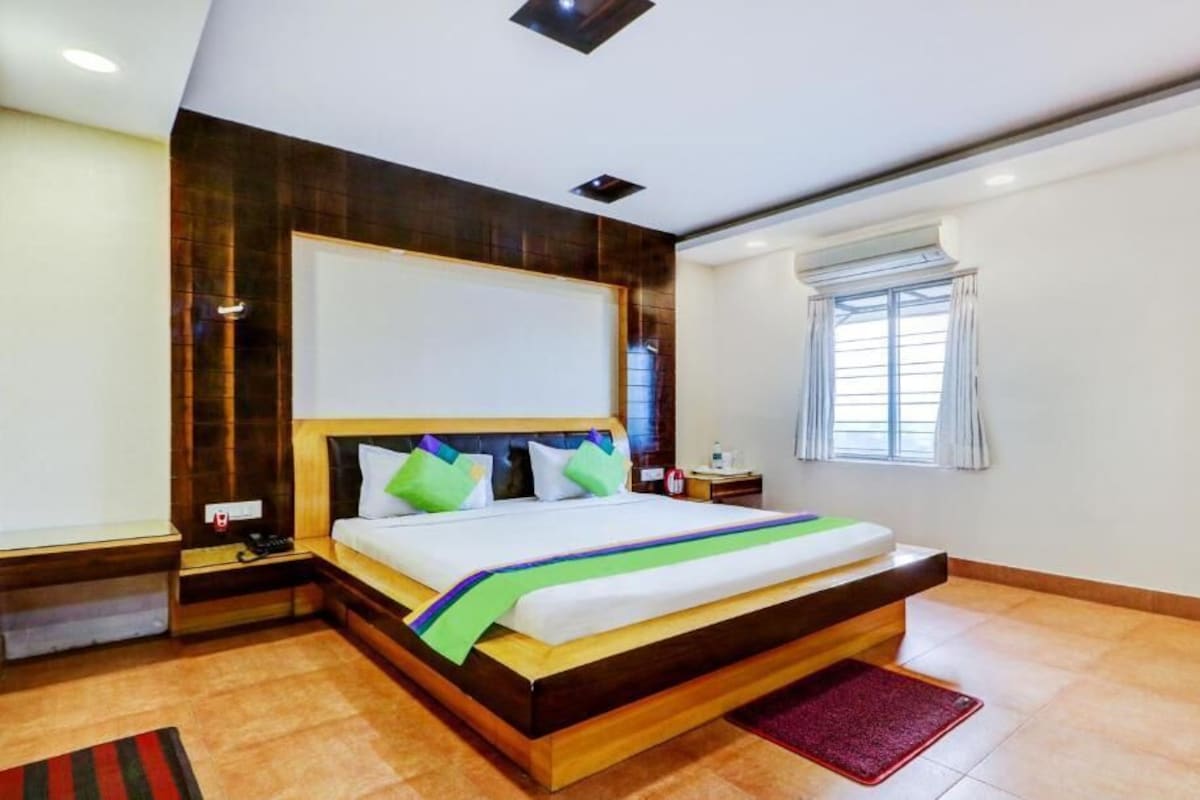 A modern bedroom with a large bed, wooden headboard, and a window with curtains.