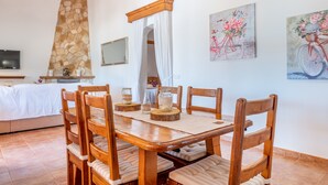 Zona pranzo con tavolo e sedie in legno, parete in pietra e opere d'arte alle pareti.