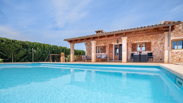 Un edificio in pietra con piscina, area relax all'aperto e vista su una collina boscosa.